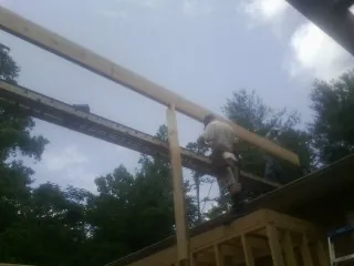 Carpenter setting a ridge beam over a new addition frame — Ice Dam Removal by Roofing Brothers in Richardson