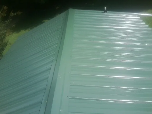 New green metal panels meeting at the ridge of a roof — Flat Roof Repair work by our crew in Richardson