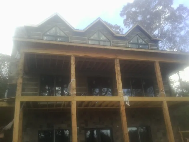 Dormers and porch framing on a large log home under construction — Roof Coating work by our crew in Richardson