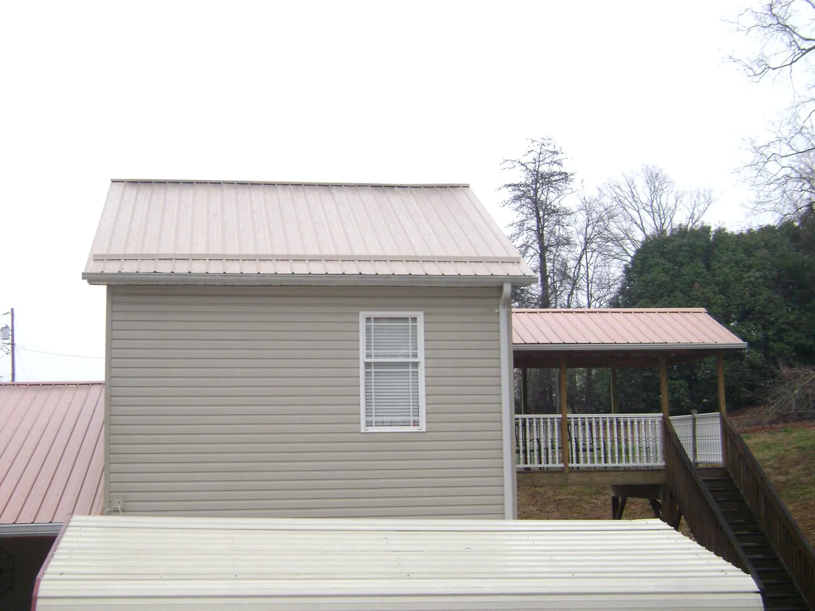 Tan metal roofs on a two story addition and attached porch, from a Roof Replacement job in Richardson
